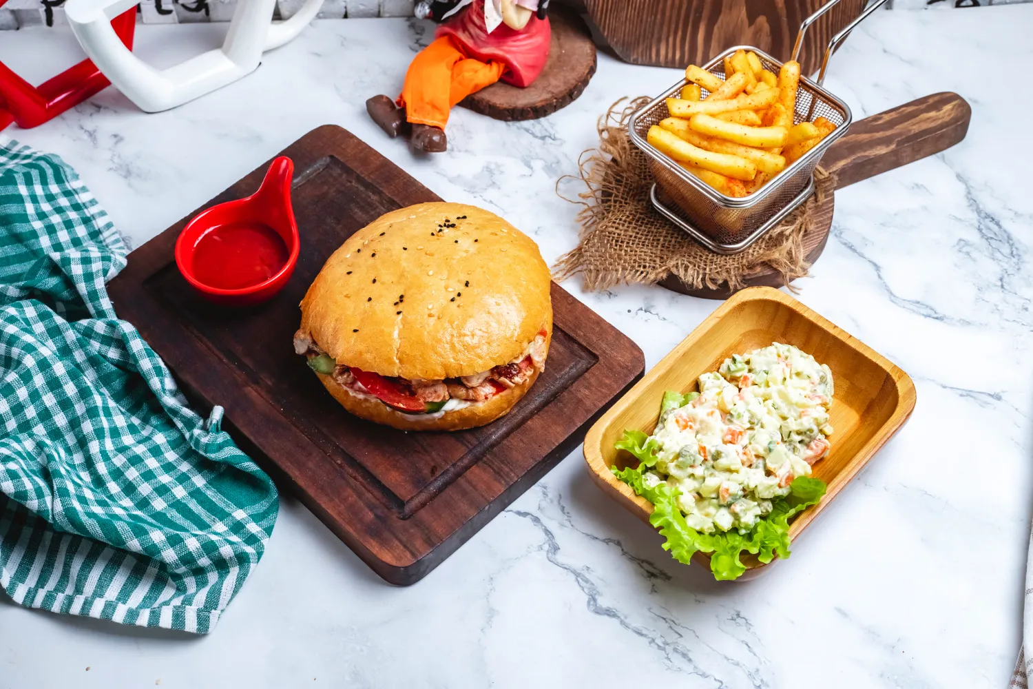 Hamburguesa jugosa con pan dorado, acompañada de papas fritas crujientes y ensalada de vegetales, presentada sobre una tabla de madera y decorada con una salsa roja. Ideal para una comida reconfortante.